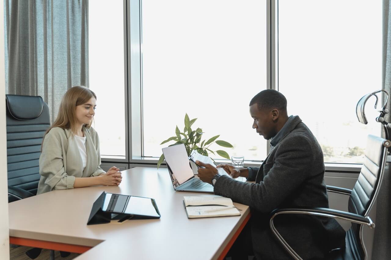 Two people sitting across a desk from eachother in a job interview.