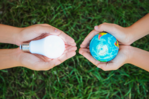 One pair of hands holding a light bulb the other holding planet Earth