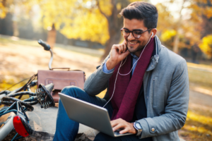 happy guy with laptop in a park