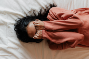 Woman in bed with hand covering her face
