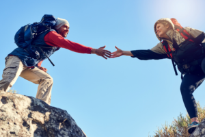 couple helping each other on a trail